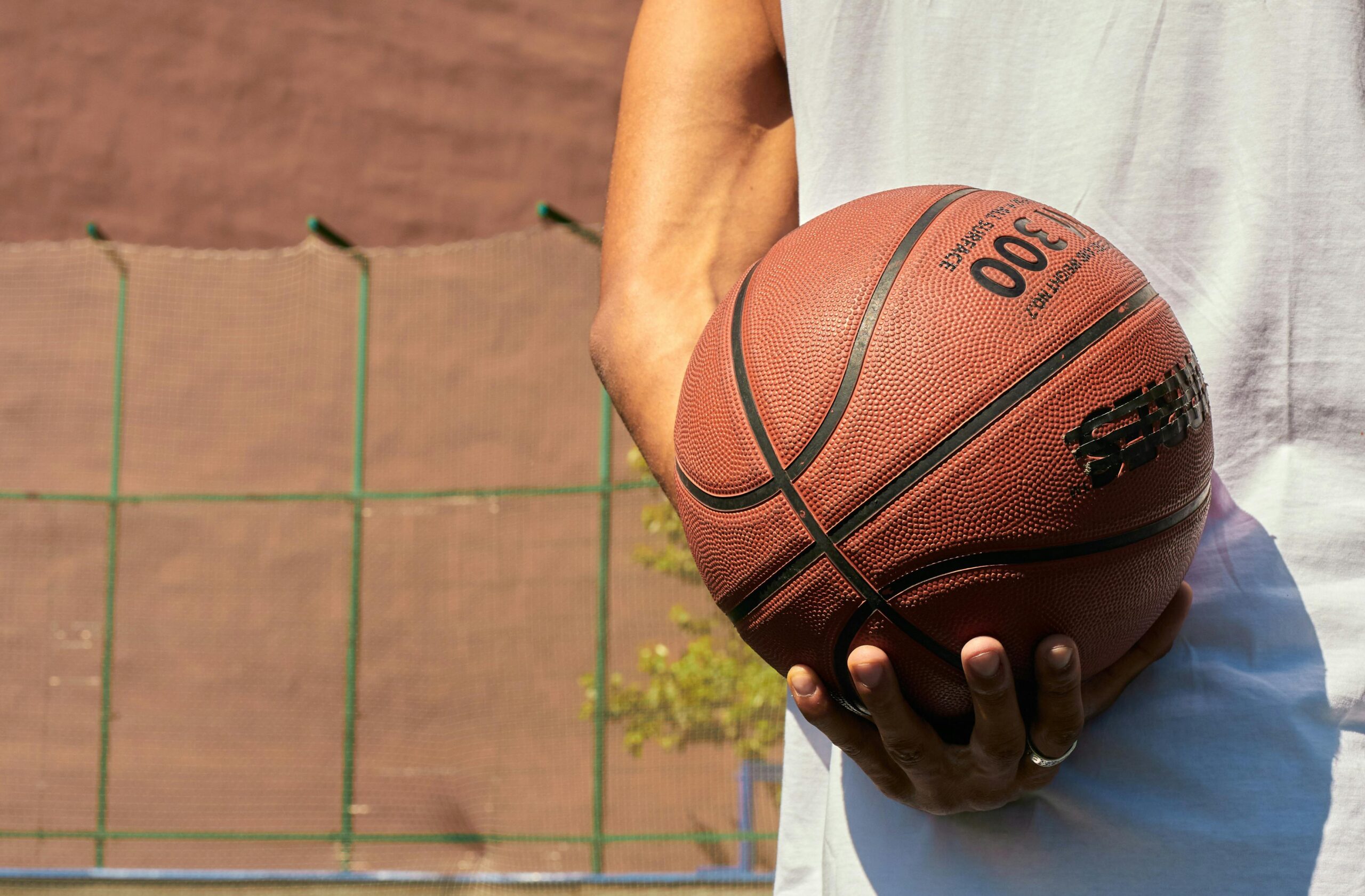 Hand holding a basketball on an outdoor court, ready for play.